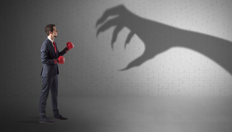 Tiny businessman fighting with scary hand shadow Tiny businessman fighting with scary hand shadow